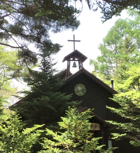 緑生い茂る木に囲まれた礼拝堂の鐘